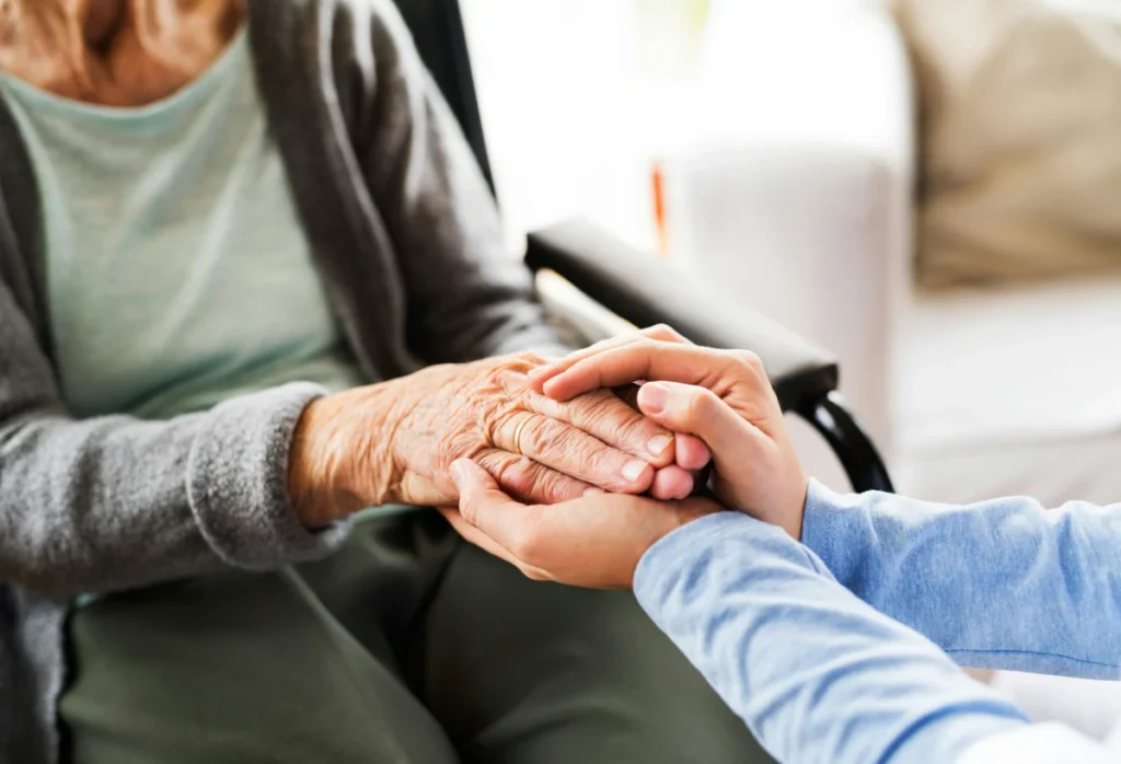 Hands gently holding elderly woman’s hand, symbolizing care, compassion, and senior support for the Call to Freedom GiveWP campaign.